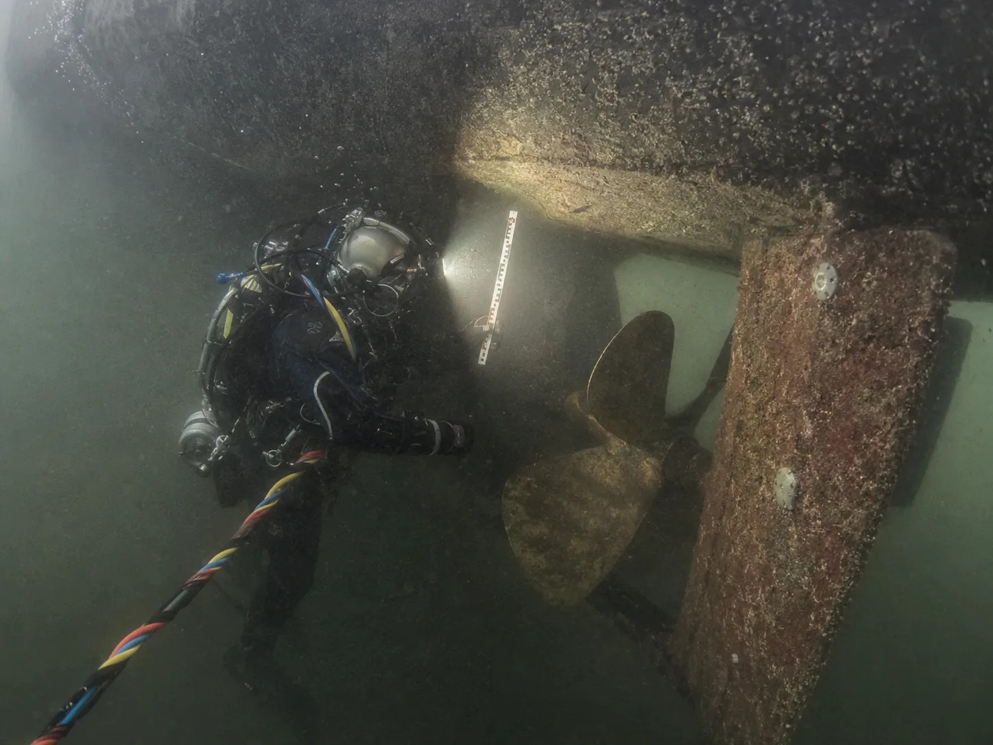Водолаз обследует подводную часть судна с замером